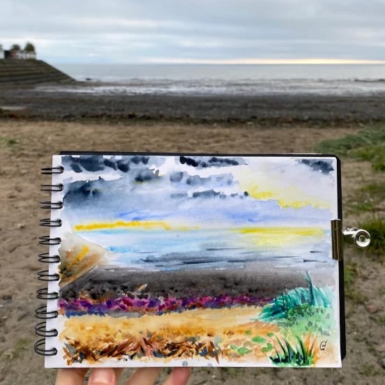 A colourful watercolour painting of a beach at sunset